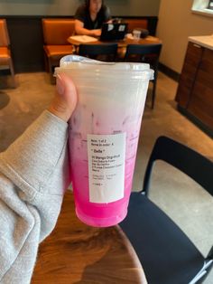 a person holding up a pink and white cup