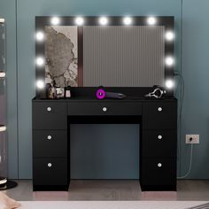 a black vanity with lights on it and a mirror behind it in a room that has blue walls