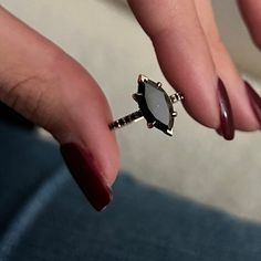 a woman's hand holding a ring with a stone in the middle and diamond accents on it