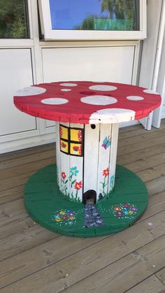 a red and white table sitting on top of a wooden floor next to a window