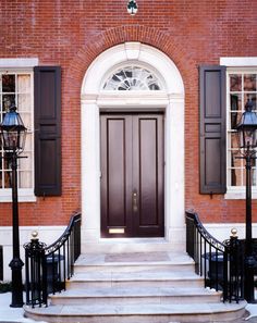 a red brick building with black wrought iron railings and two lamps on either side