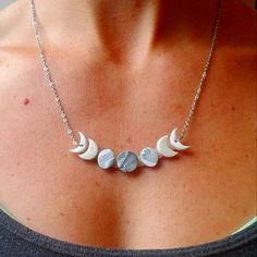 a woman wearing a necklace with three moon charms on it