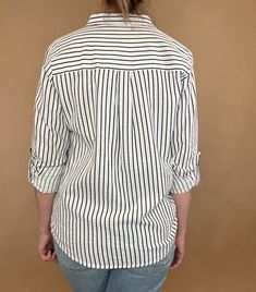 The Marina top is effortlessly beautiful with textured stripes, a split hem & a single chest pocket. Made from 100% cotton, this stylish striped shirt is versatile enough to pair with any casual denim and sandals or work wear. Let it be your go-to piece for classic, effortless fashion. Details: 100% Cotton Button up blouse Single front pocket Split hem Roll tab sleeves Fit: true to size, Amber is modeling size Small. Contents: 100% Cotton Imported Trendy Relaxed Fit Top With Vertical Stripes, Casual White Blouse With Vertical Stripes, Casual Vertical Stripes Blouse For Day Out, Trendy Tops With Horizontal Stripes And Relaxed Fit, Vertical Stripes Relaxed Fit Top For Day Out, Trendy Relaxed Fit Top With Horizontal Stripes, Relaxed Fit Vertical Stripes Top For Day Out, Relaxed Fit Vertical Stripe Tops For Day Out, Trendy Shirt With Vertical Stripes For Spring