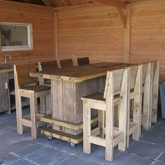 a table and chairs made out of pallets in a room with wood paneling