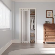 an empty room with white walls and wooden furniture in the foreground, there is a chest of drawers next to a radiator