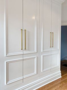 an empty room with white cabinets and wood floors