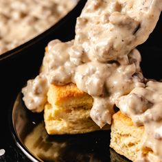 biscuits and gravy on top of each other in a black plate with two servings