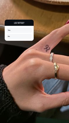 a woman's hand with a small tattoo on her left index finger and an anchor ring