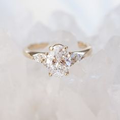 a three stone diamond ring sitting on top of a white rock covered in ice crystals