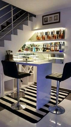 two bar stools sitting in front of a counter with liquor bottles on the shelves