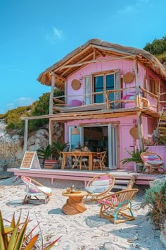 a pink house on the beach with chairs and tables