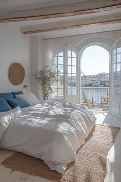 a large white bed sitting in a bedroom next to an open window with lots of natural light