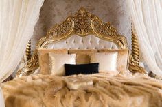 a luxurious bed with white drapes and gold headboard is adorned with faux fur