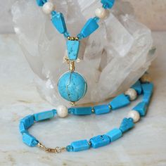 "Bold geometric shapes and bright blue genuine turquoise stone make this necklace a fun, artsy piece of jewelry.  I have used a combination of real blue chalk turquoise, cream-colored river stone and turquoise blue Czech fire-polished beads. The necklace is accented with gold-filled findings. A beautiful chalk turquoise sphere hangs in the center and is artistically wrapped with gold-filled jeweler's wire. This 24-inch chalk turquoise necklace fastens with a gold-filled lobster claw clasp.  Neck Blue Howlite Round Bead Jewelry, Blue Turquoise Howlite Necklace With Round Beads, Blue Howlite Round Beaded Jewelry, Blue Howlite Jewelry With Round Beads, Beaded Turquoise Howlite Necklace, Blue Turquoise Wire Wrapped Necklace With Round Beads, Blue Turquoise Necklace With Wire Wrapped Round Beads, Howlite Round Beads For Jewelry Making, Blue Beaded Howlite Necklaces