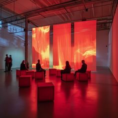 people are sitting on benches in front of large red and orange screens that look like fire