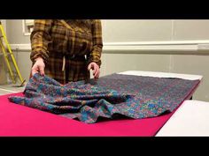 a woman is cutting fabric on top of a table