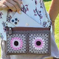 a woman is holding a crocheted purse with an iphone in the center and flowers on it