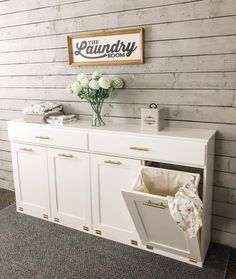 a white cabinet with some flowers on top and a sign above it that says laundry