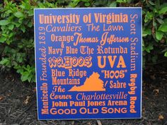 a blue sign with orange and white writing on it in front of some bushes or trees