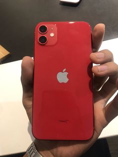 a person holding an apple phone in their hand, with the back cover partially open