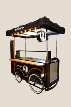 an old fashioned ice cream cart with lights on it's roof and wheels, in front of a gray background