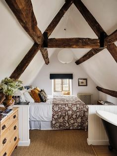 a bedroom with exposed wooden beams and a bed in the corner, next to a bathtub