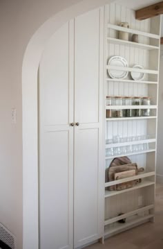 an arched doorway leads into a white pantry