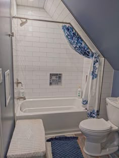 a white toilet sitting next to a bath tub in a bathroom under a slanted ceiling