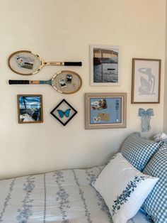 a bed with blue and white pillows, pictures on the wall and tennis rackets hanging above it