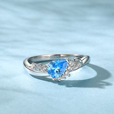 an oval shaped blue topazte and diamond ring on a light blue cloth background