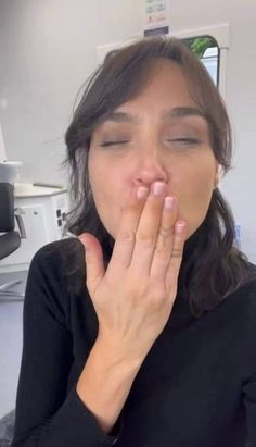 a woman is holding her hands to her mouth