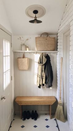 a coat rack and bench in a white entryway with black and blue floor tiles