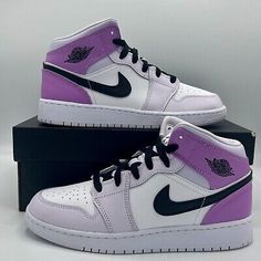 a pair of purple and white shoes on top of a black shoe box in front of a