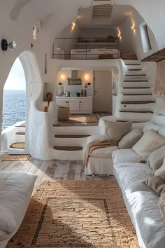 a living room filled with lots of furniture next to an ocean side kitchen and stairs