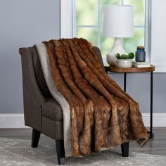 a chair with a blanket on top of it in front of a table and window