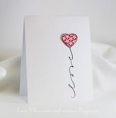 a white card with a red heart and the word love written in black ink on it