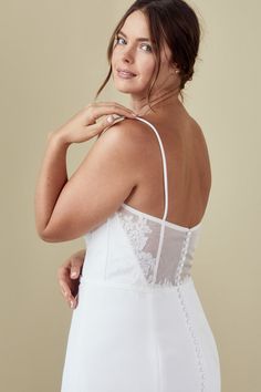 a woman in a white dress posing with her hand on her hip and looking off to the side