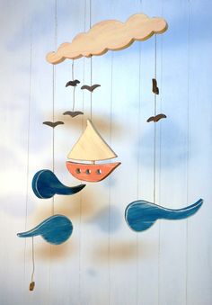 a wind chime hanging from the ceiling with birds flying around it and a sailboat in the sky