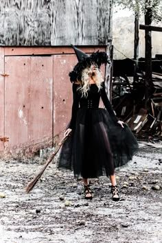 a woman in a witch costume holding a broom and wearing a black dress with long sleeves