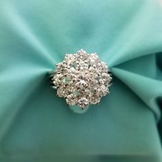 a diamond ring sitting on top of a blue cloth covered in green satin material,