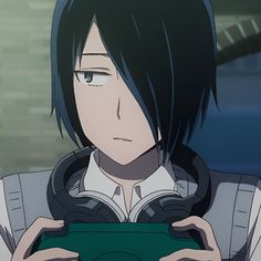 an anime character with black hair holding a green object in his hands and looking at the camera