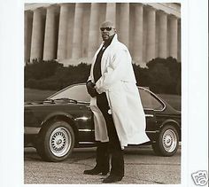 a black and white photo of a man standing next to a car in front of the lincoln memorial