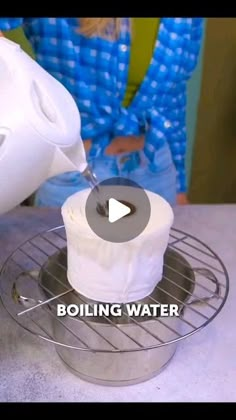 a person is pouring water into a container on top of a wire rack with a roll of toilet paper in it