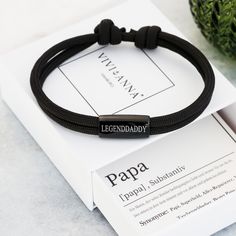 Überrasche deinen Papa dann zum Vatertag oder seinem Geburtstag mit diesem schlichten Armband besteht aus hochwertigem Segeltau und Edelstahl.  Mit einer liebevollen Papa-Definitionskarte kannst du dich bei deinem Papa bedanken und ihm mitteilen, wie toll er ist! Die Edelstahlperle können wir nach deinen Wünschen gravieren. Dadurch wird aus dem Armband ein individuelles Schmuckstück. Beiderseitige Gravur ist möglich. Es ist hautfreundlich und angenehm zu tragen. Durch leichtes Ziehen an den zwei Knoten kann die Größe des Armbands ganz einfach verstellt werden.  Das Armband ist langlebig und 100%  wasserfest, kann daher auch beim Duschen, Schwimmen und Sport getragen werden. ✧ Maße * Stärke des Segeltau: ca. 4mm * Größe der Perle : ca. 10x20 mm * Größe des Armbands: 14 bis 22 cm verstellbar Adjustable Bracelet With Letter Print For Personalized Gift, Personalized Gift Bracelets With Letter Print, Adjustable Letter Print Bracelets For Personalized Gifts, Adjustable Black Bracelet With Engraving Option, Gift Black Name Bracelet With Custom Text, Adjustable Letter Print Bracelets Gift, Adjustable Engraved Black Name Bracelet, Customizable Black Name Bracelet For Father's Day, Black Bracelets With Engraving Option For Personalized Gift