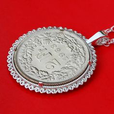 a silver coin is sitting on a red surface and has a chain attached to it