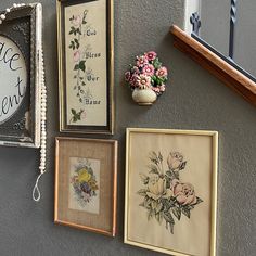 several framed pictures are hanging on the wall next to a clock and vase with flowers