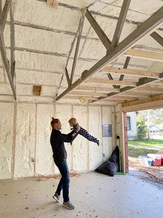 a woman holding a baby in her arms while standing inside of a room under construction