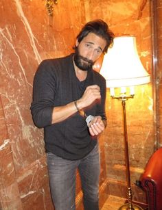 a man with a beard standing next to a lamp