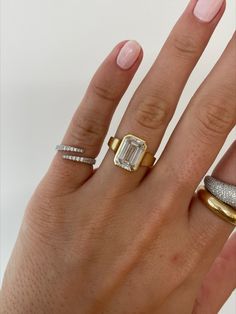 a woman's hand with three different rings on it and one diamond ring in the middle