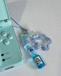 a video game remote sitting next to a bottle of water and a keychain